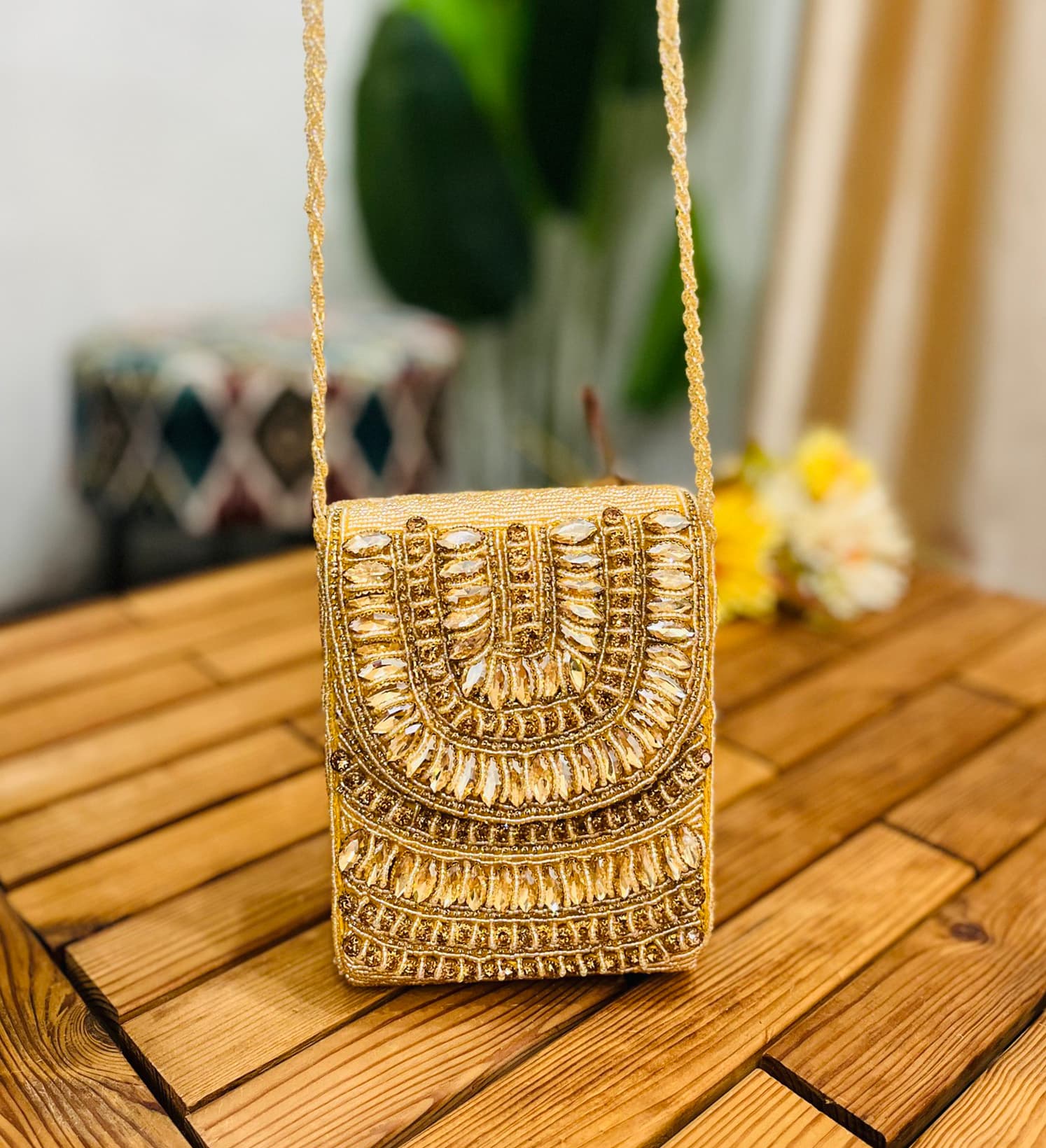 Golden crystal and beaded statement clutch with intricate design, featuring sparkling accents and elegant clasp, against