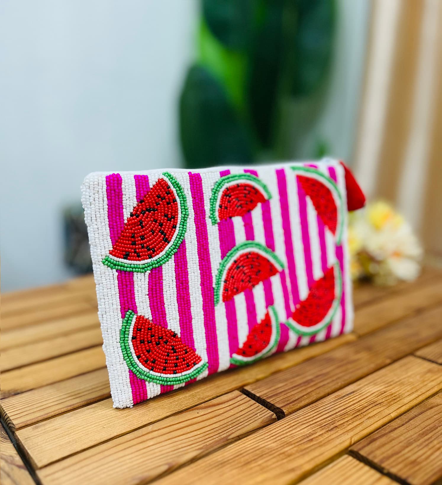 A colorful hand-beaded pouch featuring a vibrant watermelon motif, showcasing red, green, and black beadwork on a zippered